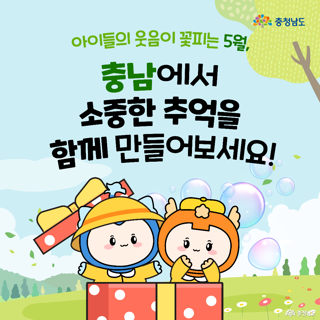 충청이와 충나미가 커다란 선물 상자에서 튀어나와 웃고 있으며, “소중한 추억을 충남에서 함께 만들어보세요!”라는 문구가 중앙에 있다. 5월 어린이날 시즌의 마무리 인사 이미지이다. 배경은 비눗방울과 푸른 자연이다.