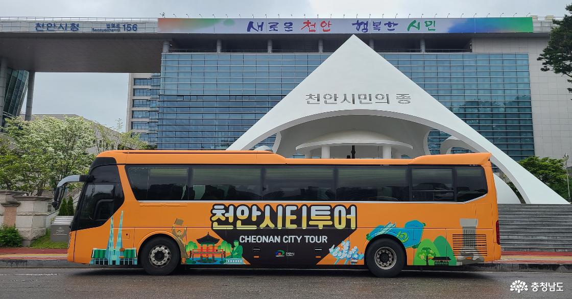 천안시청 시민의 종 앞에 주차되어 있는 주황색 천안시티투어 버스.